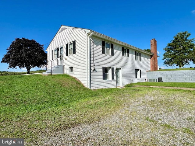 view of home's exterior with cooling unit and a lawn