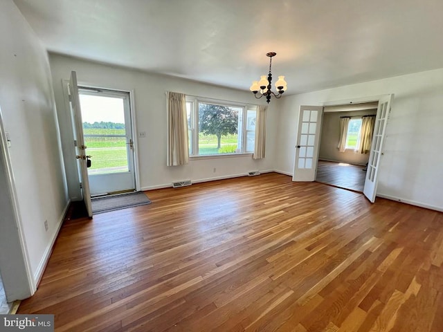 interior space with a notable chandelier, french doors, and hardwood / wood-style flooring