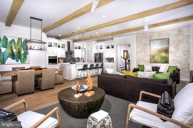 living room with beamed ceiling, light hardwood / wood-style flooring, and sink