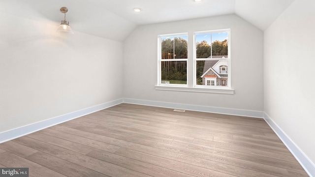 additional living space with hardwood / wood-style flooring and vaulted ceiling