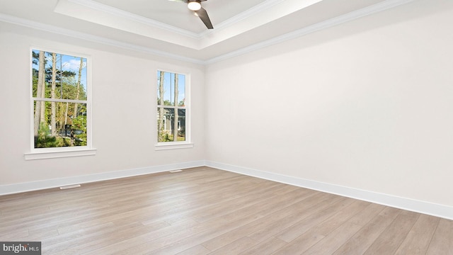 empty room featuring ceiling fan, light hardwood / wood-style floors, crown molding, and a tray ceiling