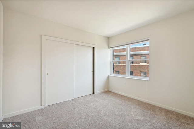 unfurnished bedroom with a closet and light colored carpet