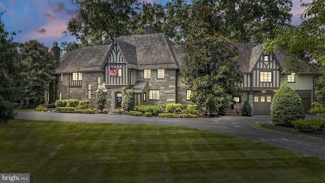 english style home with a garage and a lawn