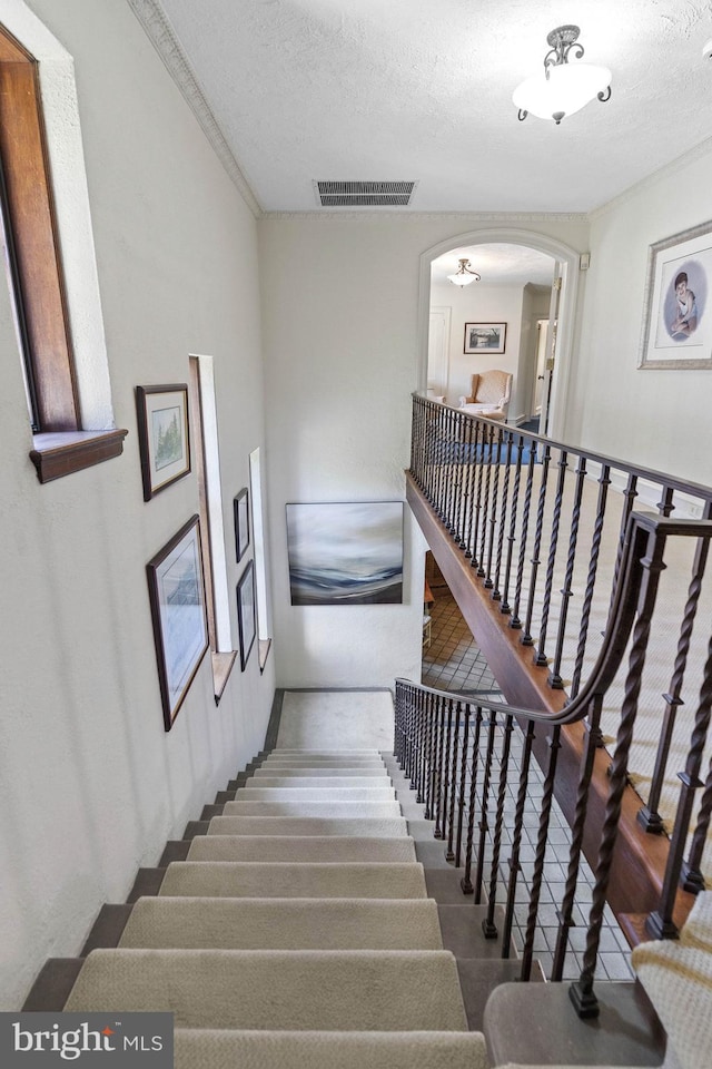 stairs featuring a textured ceiling