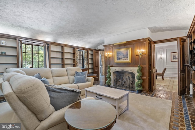 living room featuring vaulted ceiling, a textured ceiling, and built in shelves