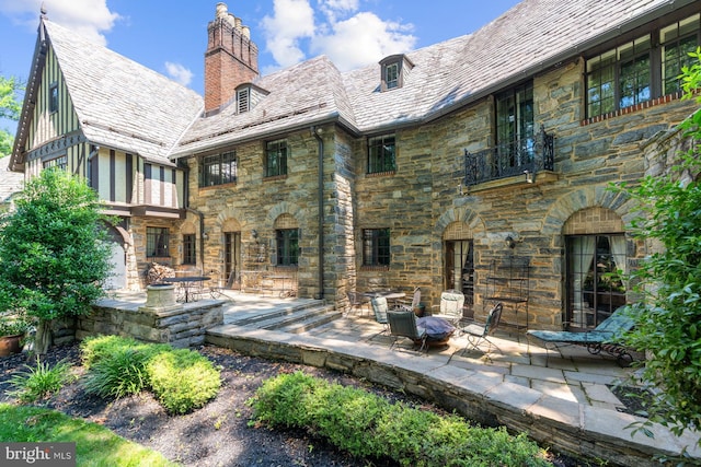 rear view of property with a fire pit and a patio