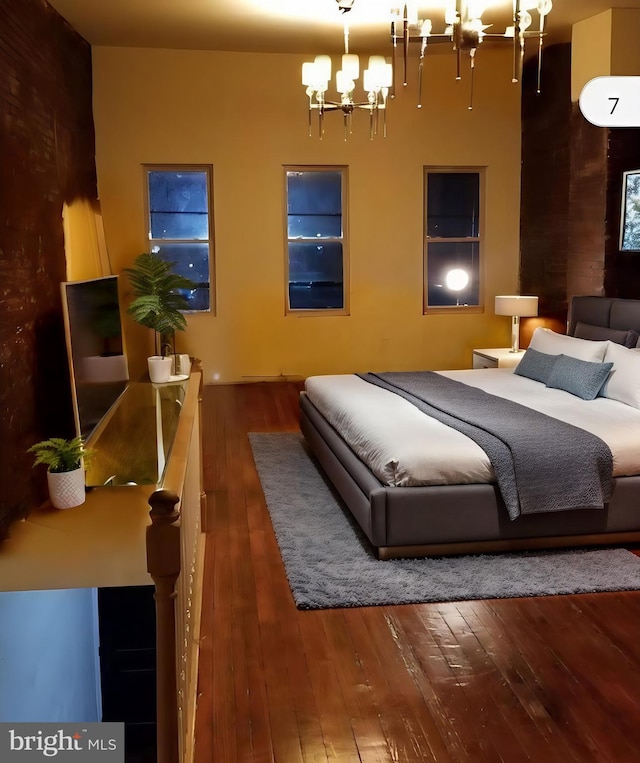 bedroom with hardwood / wood-style flooring and an inviting chandelier