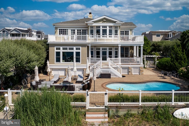 back of property featuring a balcony, a fenced in pool, and a patio