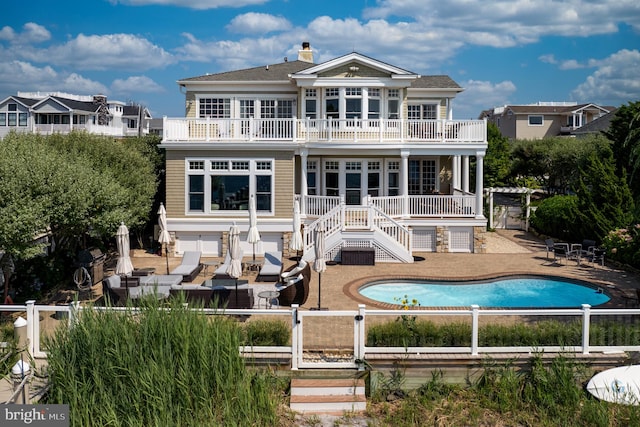 rear view of house featuring an outdoor pool, fence, and a balcony