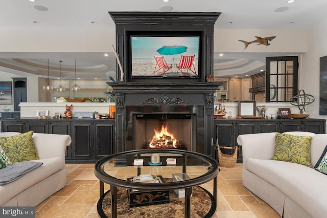 living room featuring stone tile floors, a raised ceiling, and crown molding