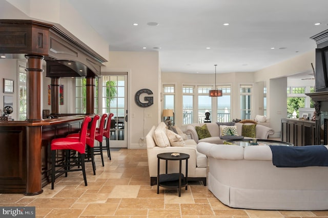 living room featuring a bar, plenty of natural light, a fireplace, and stone tile flooring