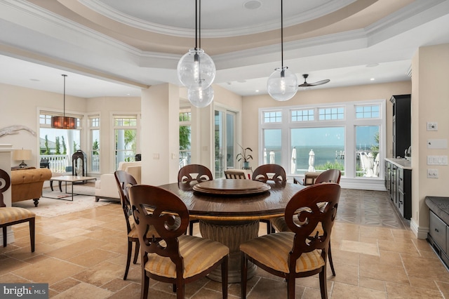 dining space featuring ornamental molding, a tray ceiling, stone tile flooring, and baseboards