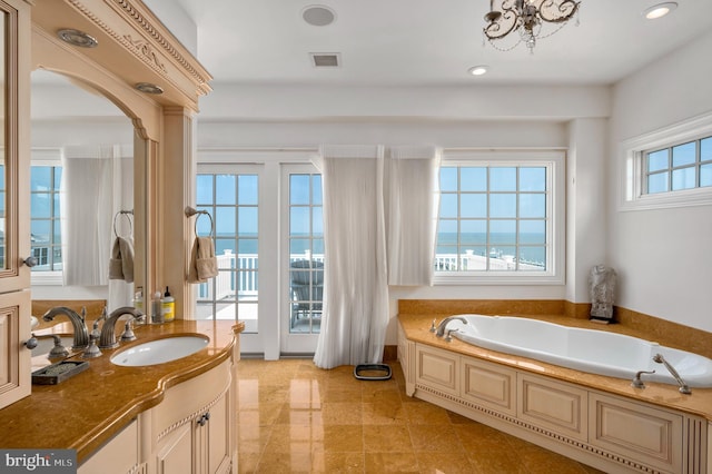 bathroom featuring a garden tub, recessed lighting, a water view, vanity, and visible vents