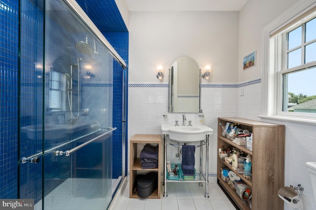 full bathroom featuring tile patterned flooring, a wainscoted wall, a sink, tile walls, and a shower stall