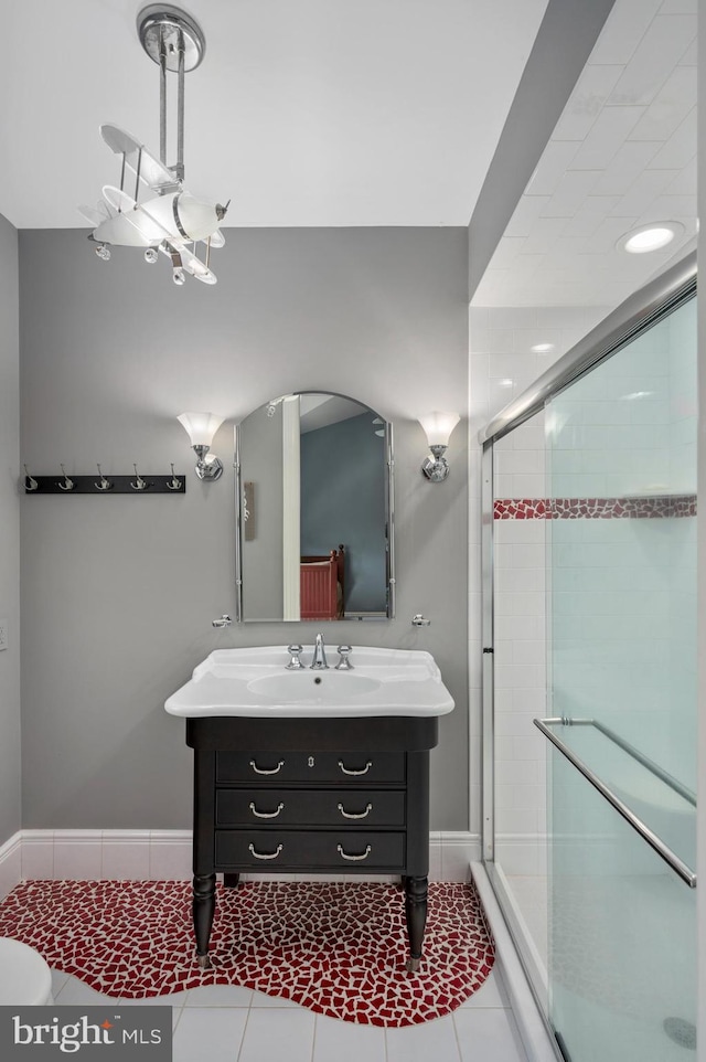 full bath featuring a stall shower, vanity, baseboards, and tile patterned floors