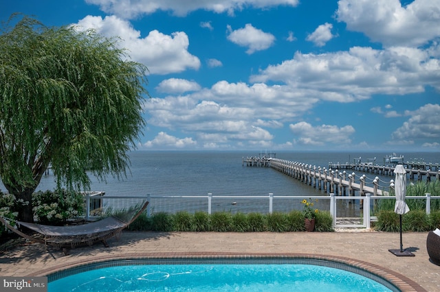 view of swimming pool with a water view and fence