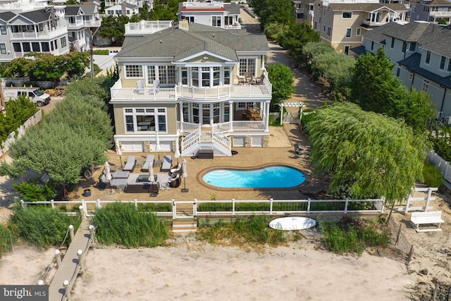 rear view of house with a balcony, a residential view, a fenced backyard, and a fenced in pool