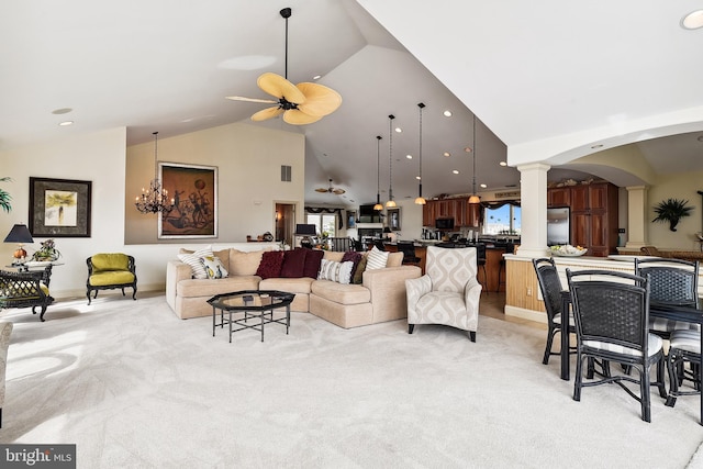 living area featuring ceiling fan with notable chandelier, arched walkways, decorative columns, and light colored carpet