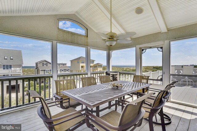 sunroom featuring lofted ceiling with beams, plenty of natural light, a residential view, and a ceiling fan