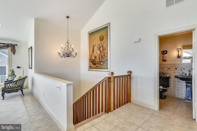 hallway with lofted ceiling, a healthy amount of sunlight, visible vents, and tile walls