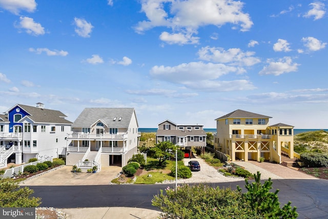 view of front facade featuring driveway, a balcony, stairs, and a residential view