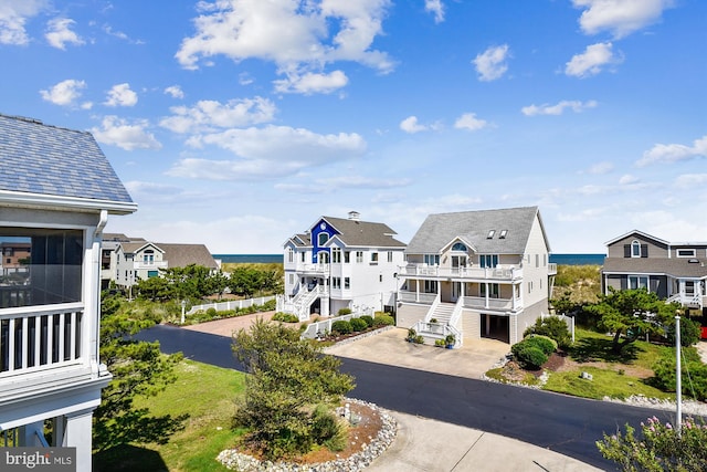 exterior space with stairs, driveway, a water view, and a residential view