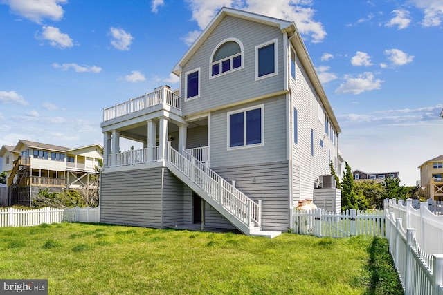 rear view of property with a fenced backyard, a yard, a balcony, and stairs