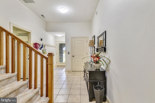 foyer with baseboards, visible vents, stairway, an AC wall unit, and light tile patterned flooring