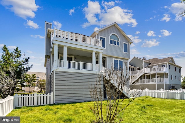 view of front facade featuring a balcony, a fenced backyard, stairs, and a front yard