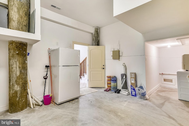 garage featuring freestanding refrigerator, electric panel, and visible vents