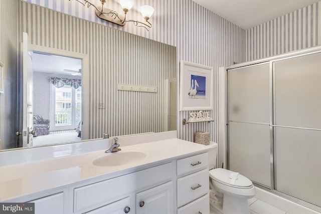 full bath featuring connected bathroom, vanity, a shower stall, and wallpapered walls