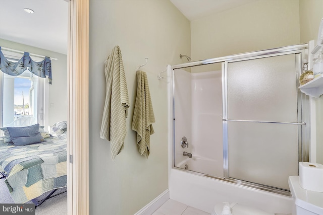 ensuite bathroom featuring bath / shower combo with glass door, tile patterned flooring, connected bathroom, and baseboards