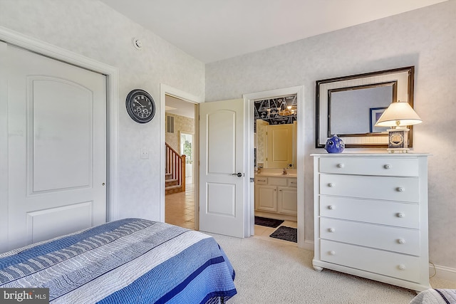 bedroom with ensuite bath, a sink, visible vents, and light colored carpet