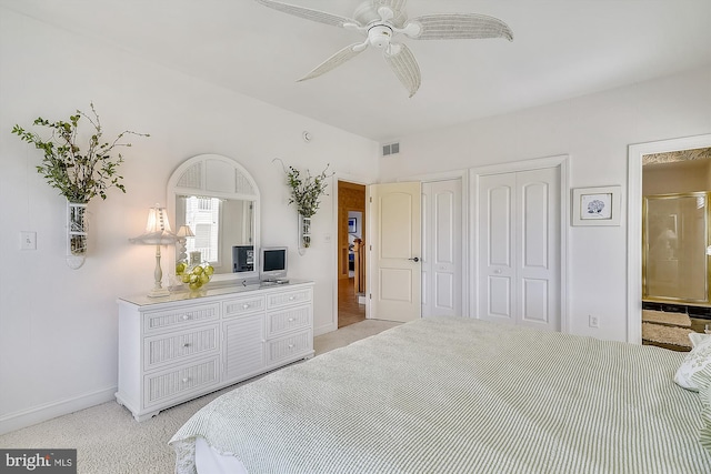 bedroom featuring visible vents, light colored carpet, two closets, and ensuite bathroom