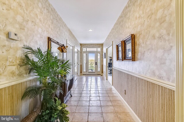 entryway with a wainscoted wall and wallpapered walls