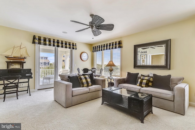 living area featuring ceiling fan, baseboards, a wealth of natural light, and light colored carpet