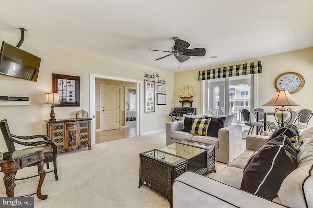 living room featuring ceiling fan, light tile patterned floors, baseboards, and light colored carpet