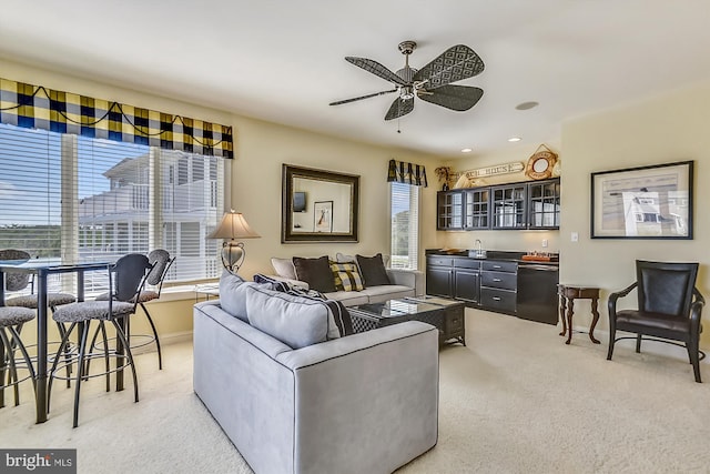 living area featuring wet bar, light carpet, ceiling fan, and baseboards