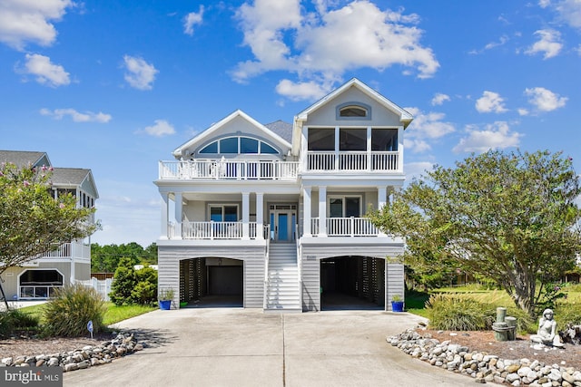 coastal home with a porch, driveway, stairway, and a garage