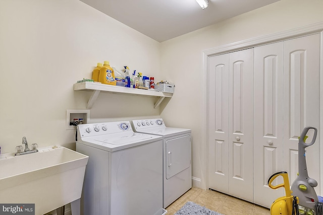 laundry area featuring washing machine and dryer, laundry area, light tile patterned flooring, and a sink