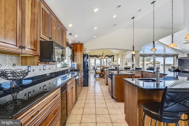 kitchen featuring dark countertops, a breakfast bar area, open floor plan, pendant lighting, and a sink