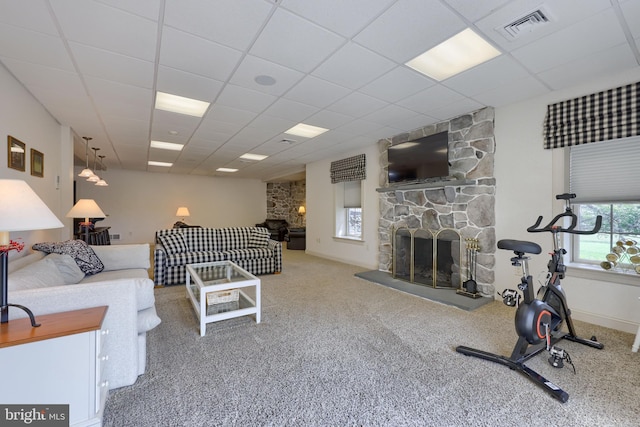 carpeted living room featuring baseboards, visible vents, a stone fireplace, and a drop ceiling