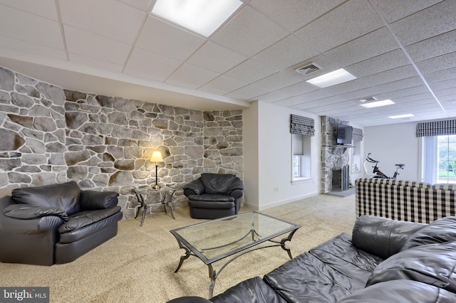 carpeted living room with a paneled ceiling, visible vents, and a stone fireplace