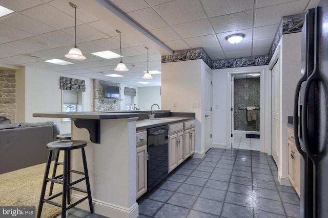 kitchen featuring open floor plan, a sink, black appliances, a peninsula, and a kitchen breakfast bar