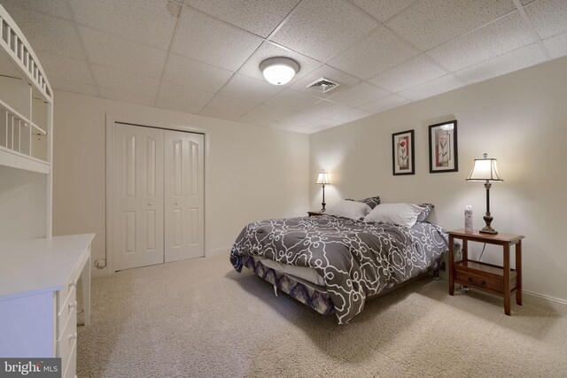 carpeted bedroom featuring a closet, a drop ceiling, visible vents, and baseboards