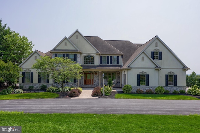 view of front of property with stone siding, a front lawn, and stucco siding