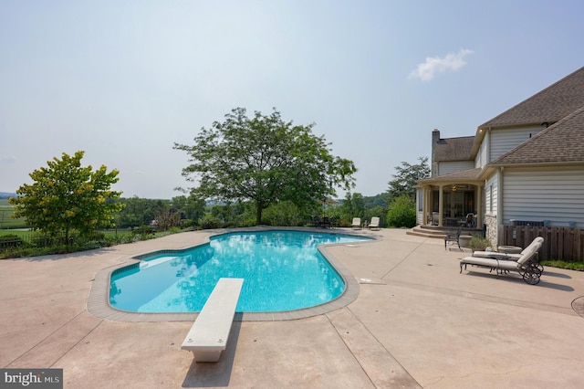 view of pool featuring a diving board, a patio area, fence, and a fenced in pool