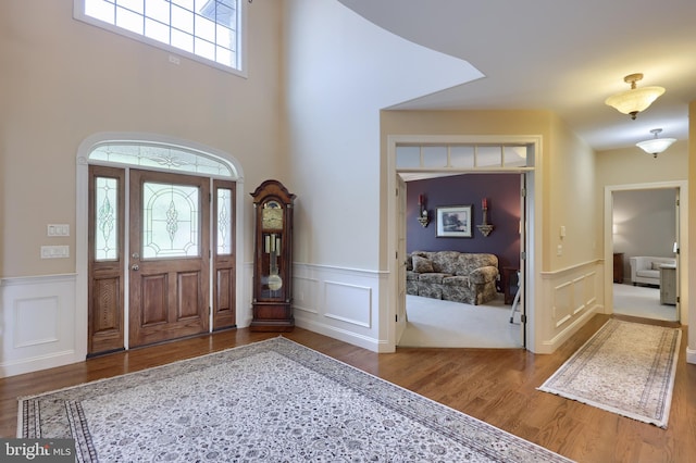 entrance foyer with a decorative wall, wood finished floors, and wainscoting