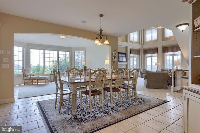 dining space with a healthy amount of sunlight, baseboards, arched walkways, and ceiling fan with notable chandelier