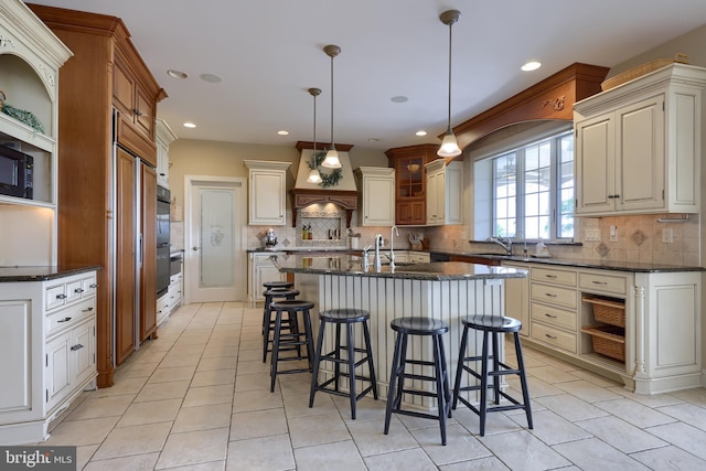 kitchen with decorative backsplash, a sink, a center island with sink, and a breakfast bar area